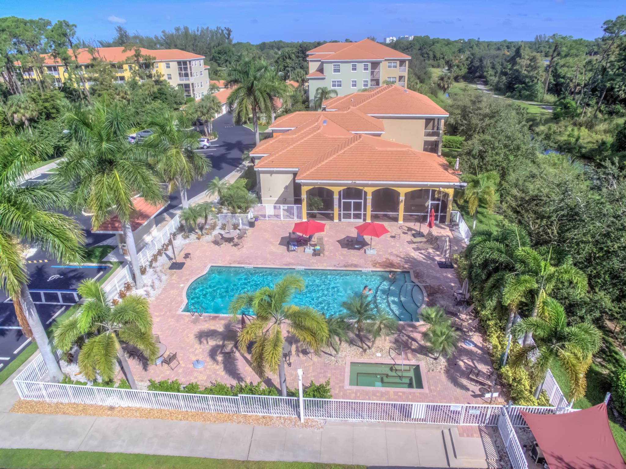 The community pool, spa, pool deck with tables and chairs and the clubhouse